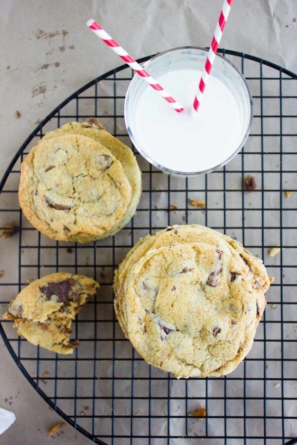 Nutella Stuffed Chocolate Chip Cookies stacked on a cooling rack with a glass of milk in the background