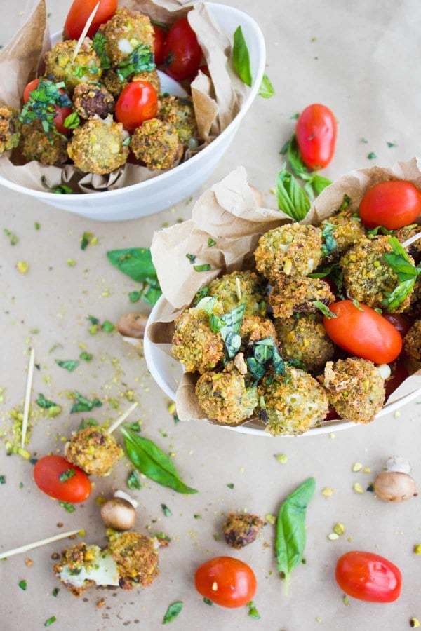 2 small oval bowls with Pistachio Fried Caprese Bites arranged with cocktail tomatoes