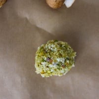 A bocconcini cheese coated in flour, pesto and pistachio ready for frying