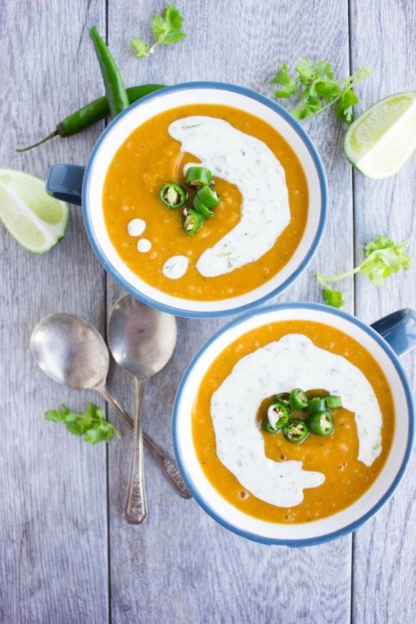 overhead shot of two bowl of healthy lentil soup with red lentils quinoa and sweet potatoes served with a sour cream drizzle 