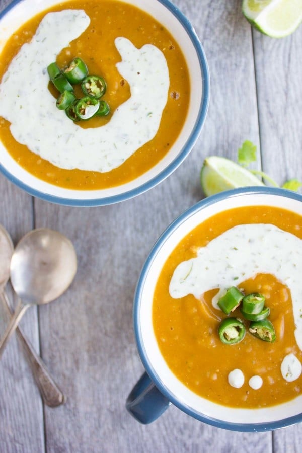 two bowl of healthy lentil soup with red lentils quinoa and sweet potatoes served with a sour cream drizzle and jalapeno slices