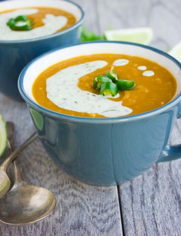 side view of a soup cup filled with healthy lentil soup drizzled with lime cilantro cream