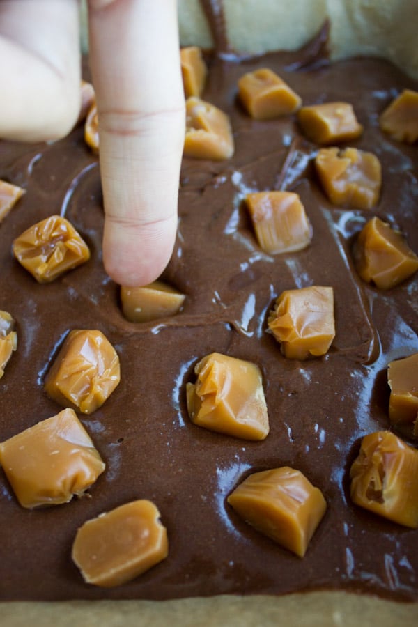 chunks of caramel being pushed into chocolaty brownie batter
