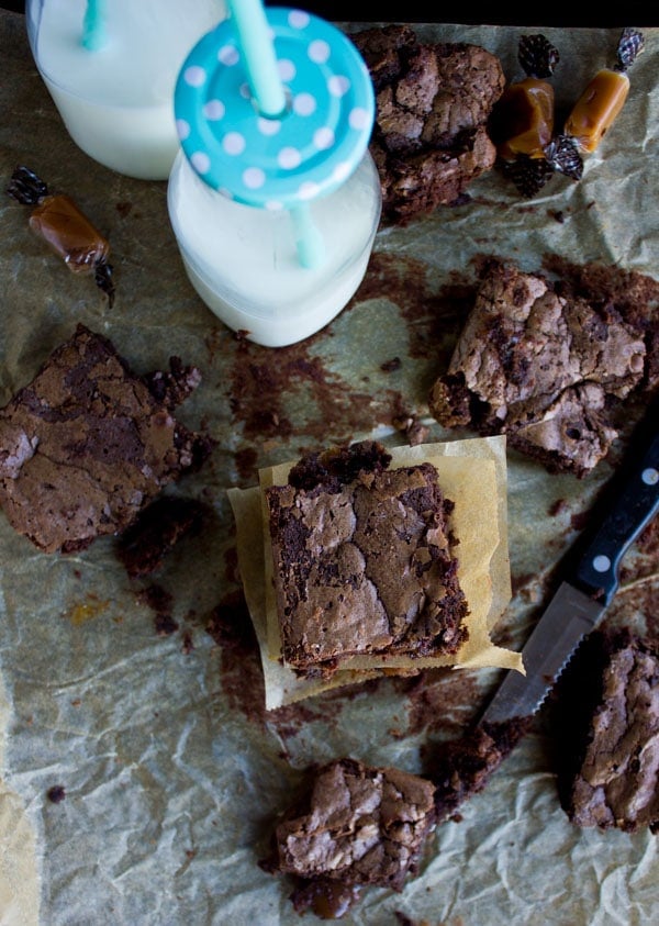 Caramel Stuffed Spiced Brownies stacked on top of each other on a baking sheet with a bottle of mild in the background