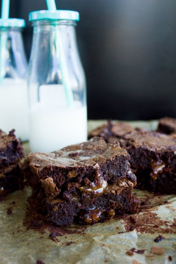 Side-view of two stacked chocolate brownies with caramel oozing out of the center 