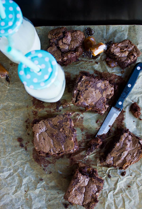 freshly baked brownies cut into squares and arranged on a parchment paper-lined sheetpan