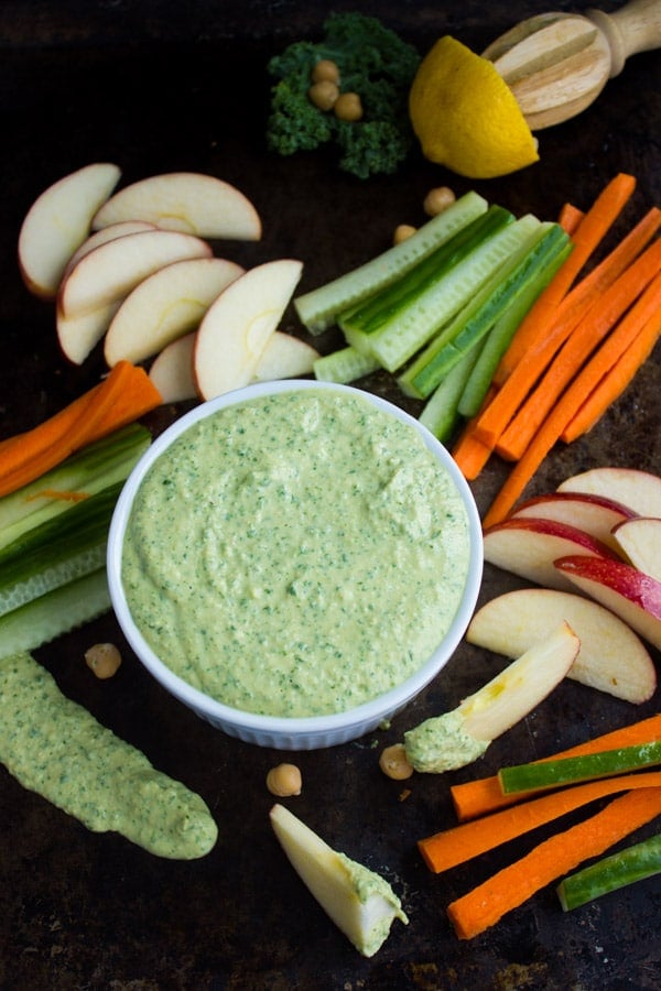 Garlic Kale Hummus Dip in a small dish with veggies sticks surrounding it