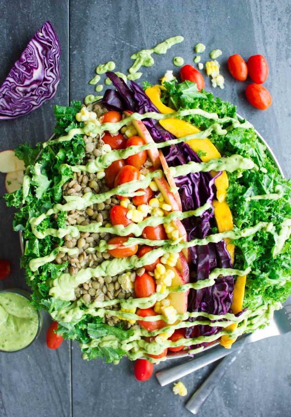 Mexican Style Lentil Detox Salad topped with creamy guacamole dressing served in a big salad bowl on a rustic dark wood table