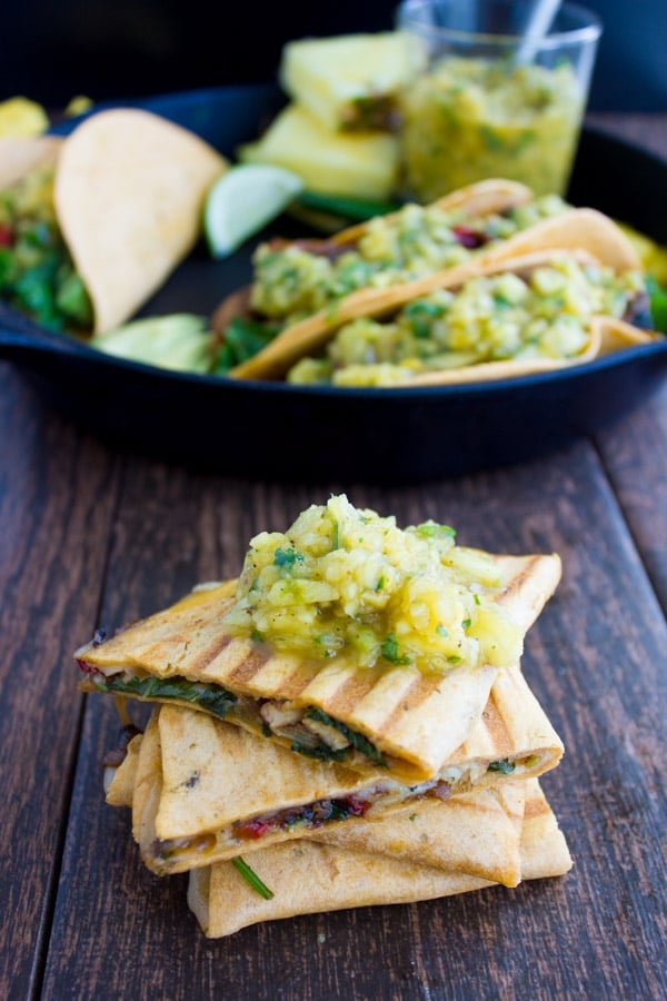 Chicken Fajita With Mango Pineapple Salsa served in hard taco shells and cut into bite sized chunks in fort of a black skillet with more fajitas