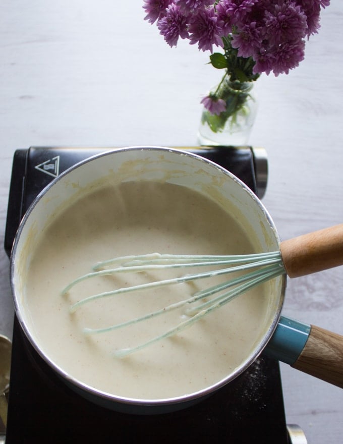 A pot with a whisk making the bechamel sauce with milk, butter and flour