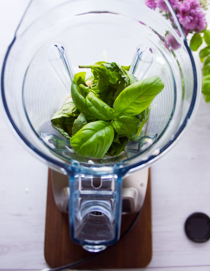 A blender with some of the béchamel sauce and lots of fresh basil ready to blend