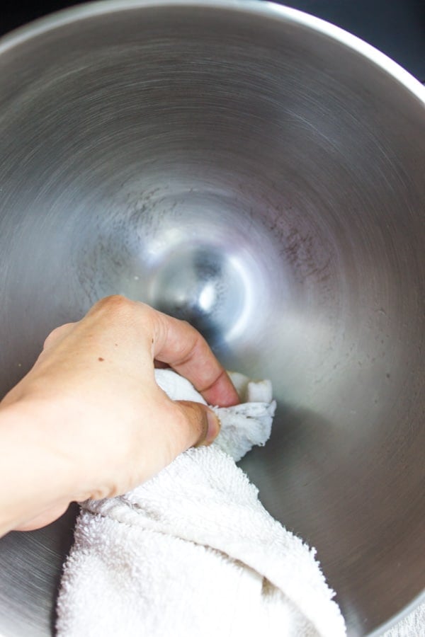 a metal bowl being cleaned with a white dishtowel