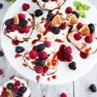 Chocolate Dipped Mini Pavlova. A 5 star delicate dessert shaped into mini hearts, dipped halfway in chocolate, topped with fresh whipped cream, berries and raspberry sauce. Get the recipe with step by step photos and tips to make the PERFECT pavlova every time! www.twopurplefigs.com