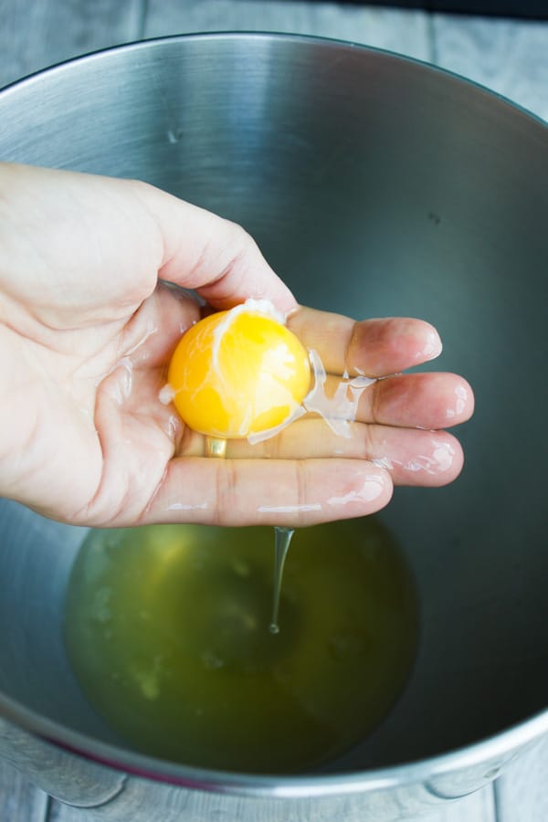 an egg yolk being separated from the whites by hand