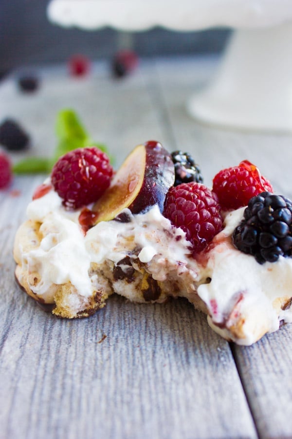 close-up of Chocolate Dipped Mini Pavlova drizzled with raspberry sauce and decorated with fresh berries and fig slices