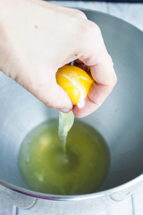 an egg yolk being separated from the whites by hand