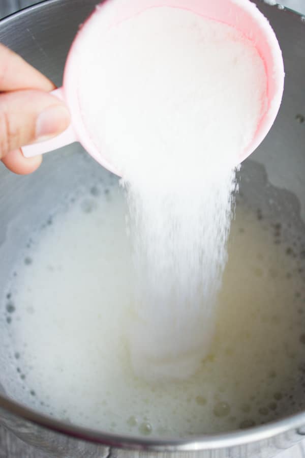 granulated sugar being poured into foamy egg whites