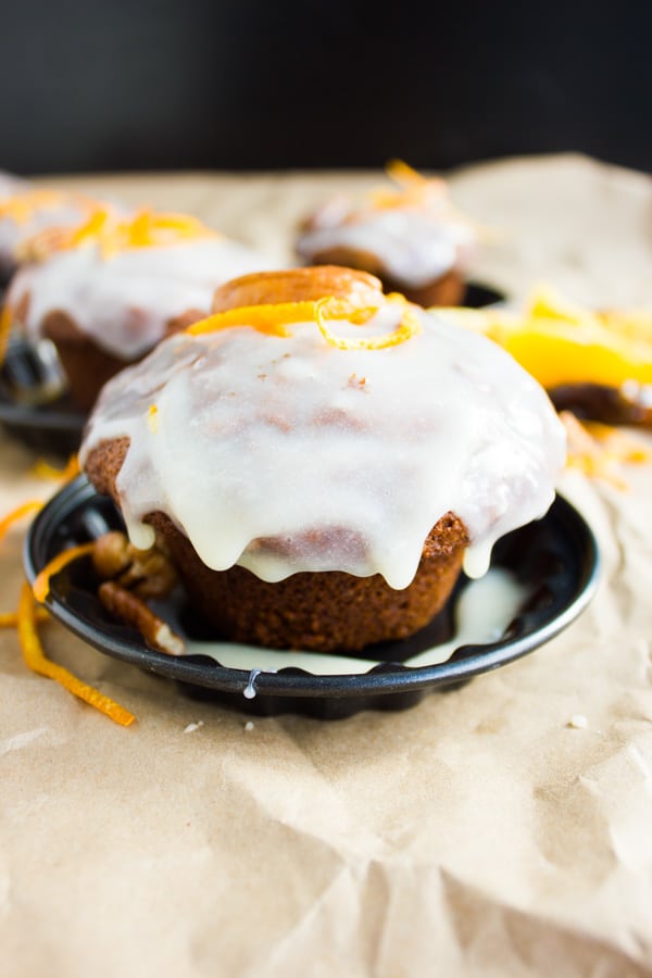 Orange Chai Spice Date Muffins studded with figs and dates and topped with orange cream cheese icing on a small plate