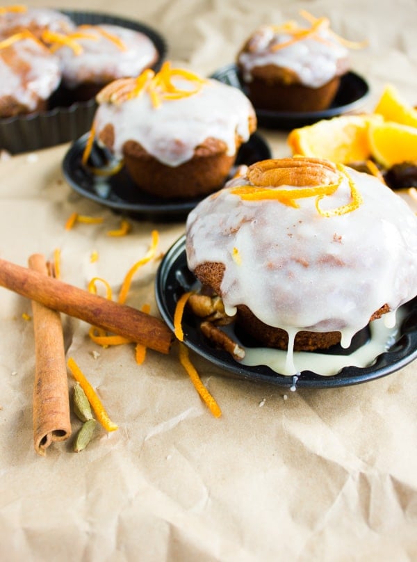 Orange Chai Spice Date Muffins with Orange Cream Cheese Icing arranged on crinkled parchment paper