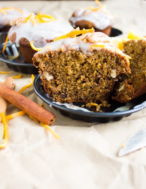 half a Orange Chai Spice Date Muffins with some grated orange zest and a cinnamon stick on the side