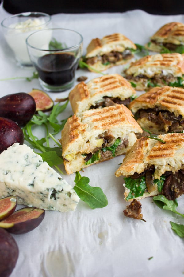 bite-sized pieces of Blue Cheese Philly Steak Sandwich arranged on parchment paper decorated with fresh figs, blue cheese and arugula