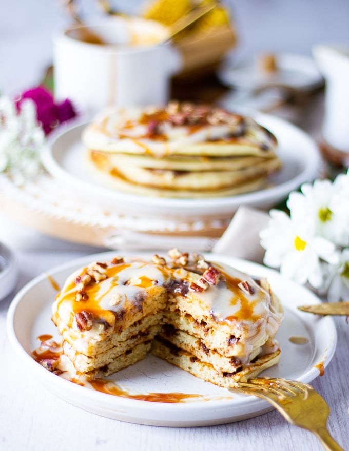 two stacks of cinnamon roll pancakes with one stack cut off 