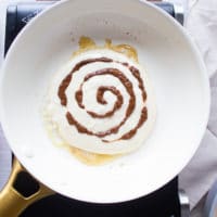 a pancake batter on a skillet and a swirl of cinnamon sugar around it