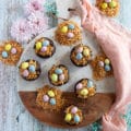 coconut brownies on a wooden board all topped and ready with coconut shreds and chocolate eggs