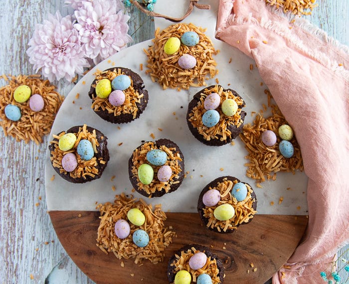 coconut brownies on a wooden board all topped and ready with coconut shreds and chocolate eggs