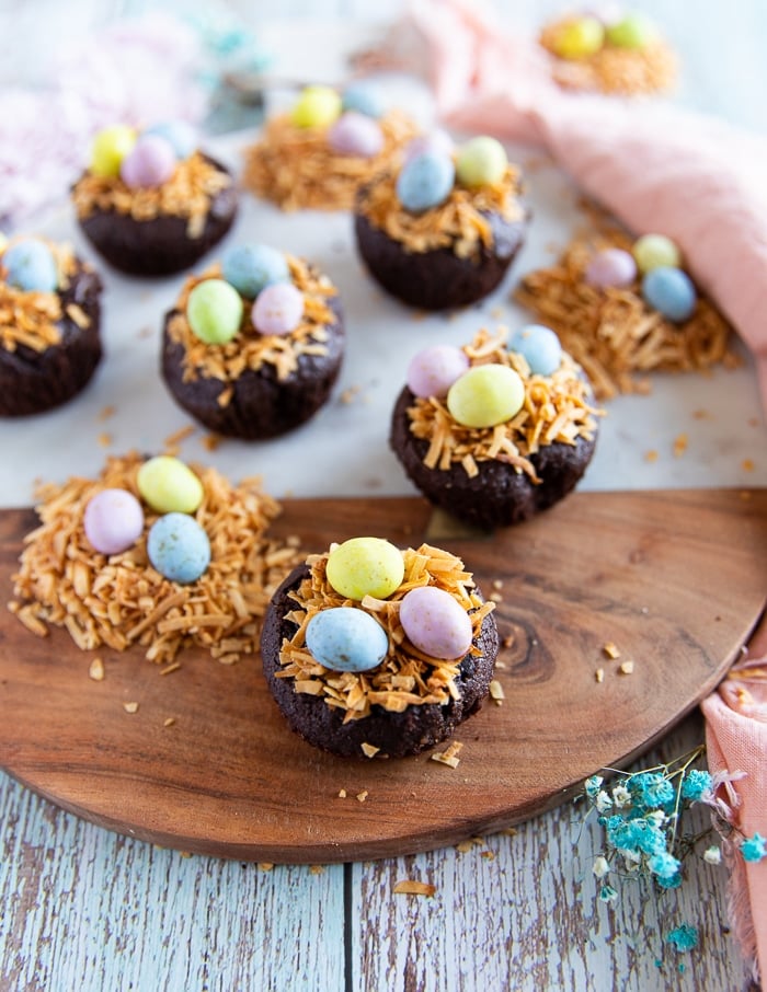 coconut brownies on a wooden board topped with toasted shredded coconut and chocolate eggs