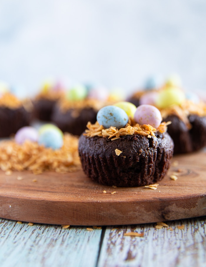 coconut brownies on a wooden board topped with coconut shreds and chocolate eggs