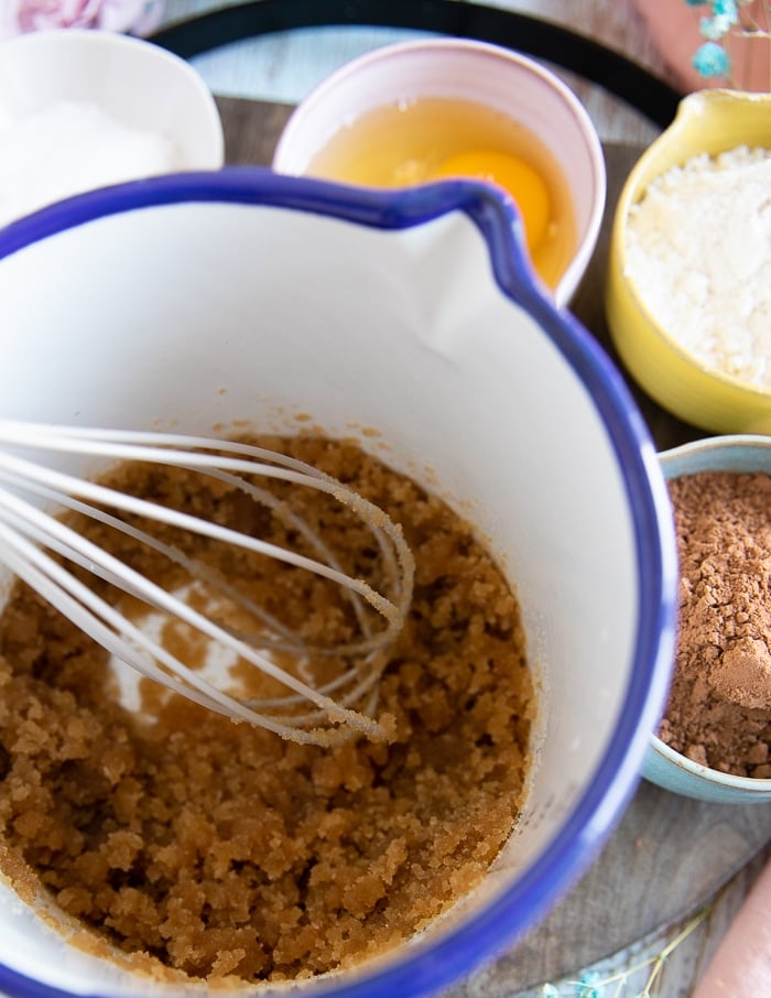 a bowl and a whisk mixing the coconut oil and brown sugar