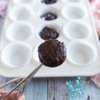 An ice cream scoop holding coconut brownie batter to place into the baking pan