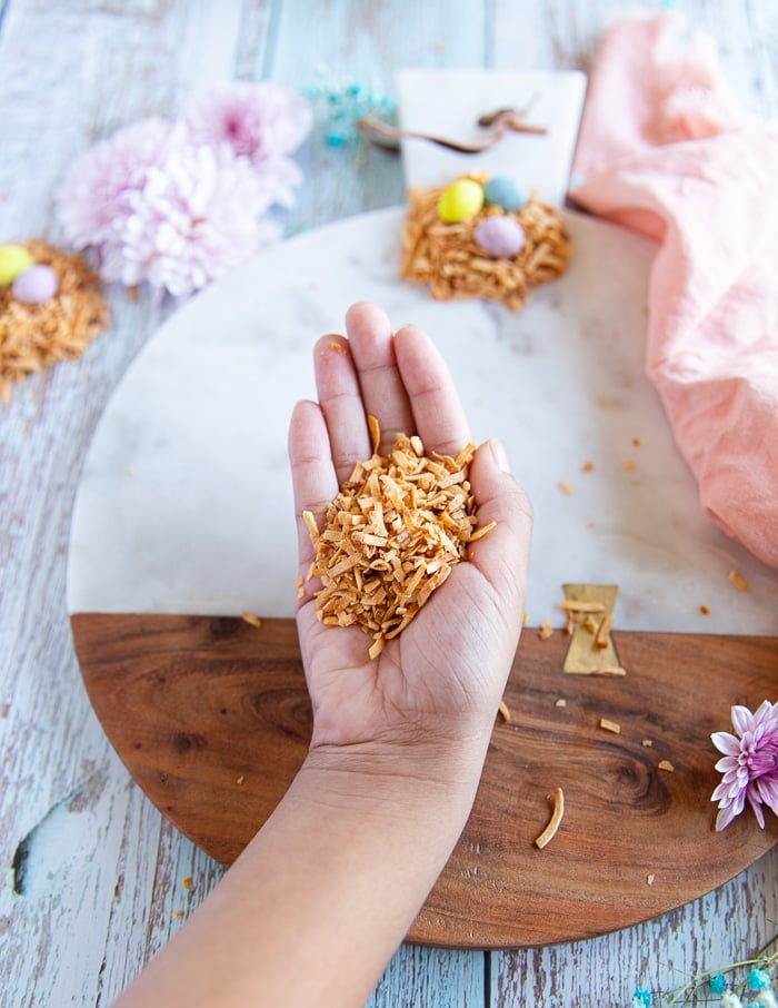 a hand holding toasted coconut flakes