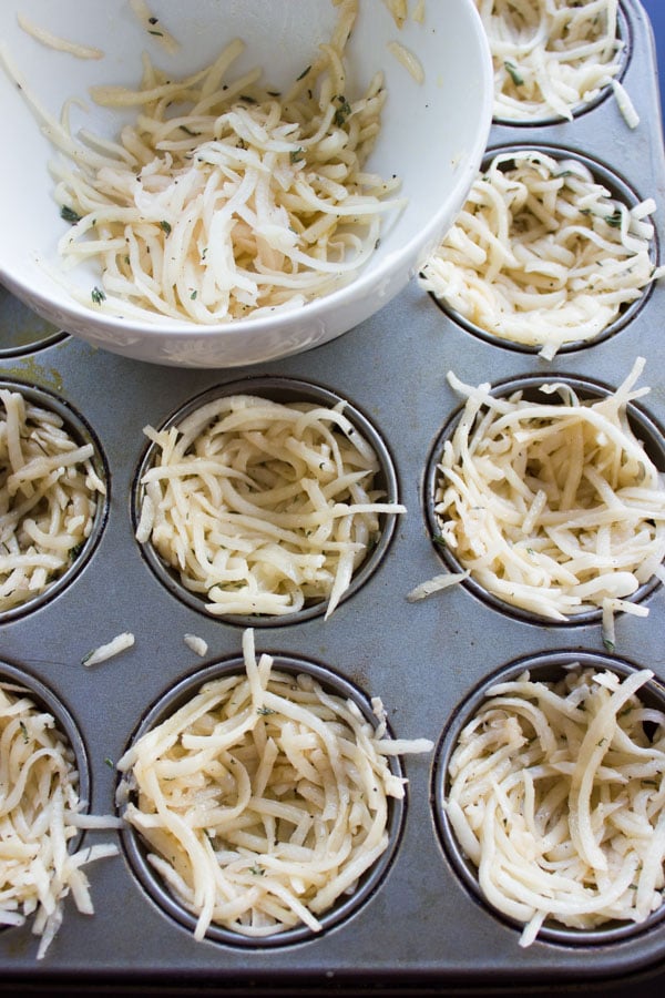 shredded potatoes being packed into a muffin pan