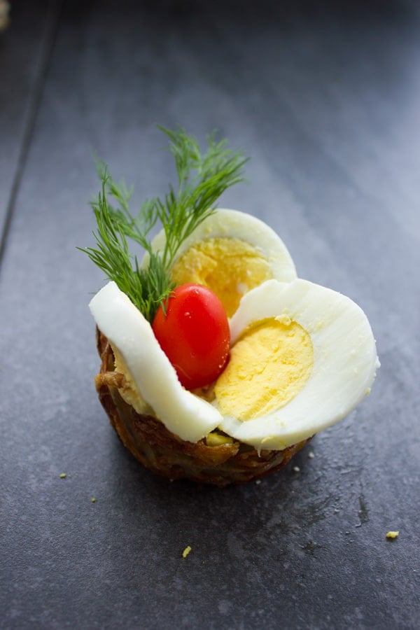 potato nests being topped with sliced Easter eggs