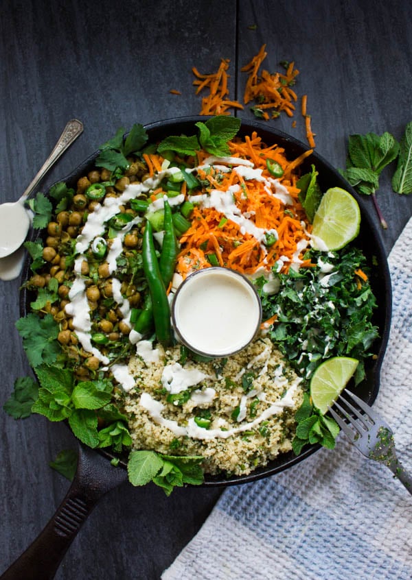 Spicy Vegan Chickpea Moroccan Couscous surrounded by carrot salad and a tahini sauce in the middle