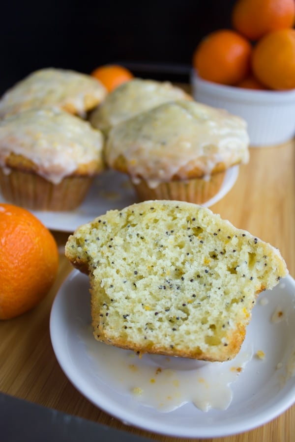 half a Ginger Clementine Lemon Poppy Seed Muffin on a small white plate, revealing the perfect fluffy crumb