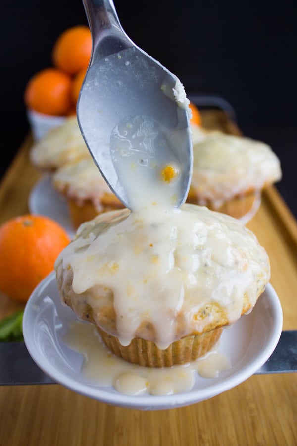 clementine glaze being drizzled on top of a lemon poppy seed muffin