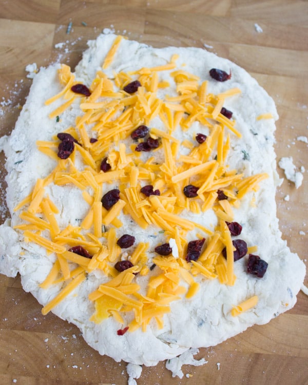 rolled out biscuit dough sprinkled with cheese and cranberries