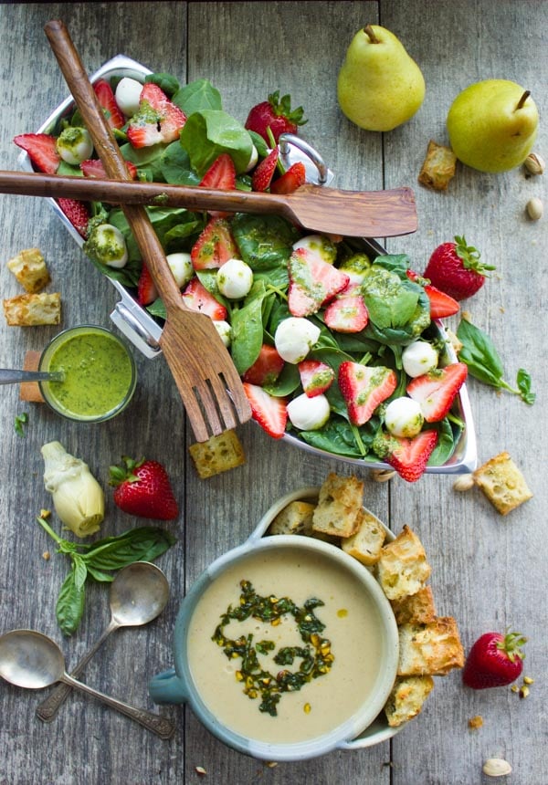 Strawberry Spinach Salad served in a boat-shaped silver bowl next to a bowl with Artichoke Soup and croutons.