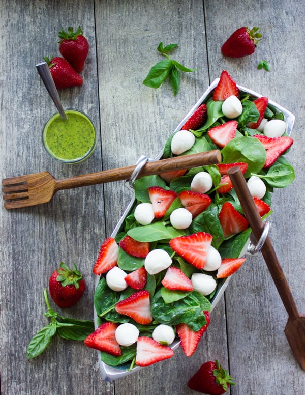Strawberry Spinach Salad arranged in a boat-shaped dish on a wood table
