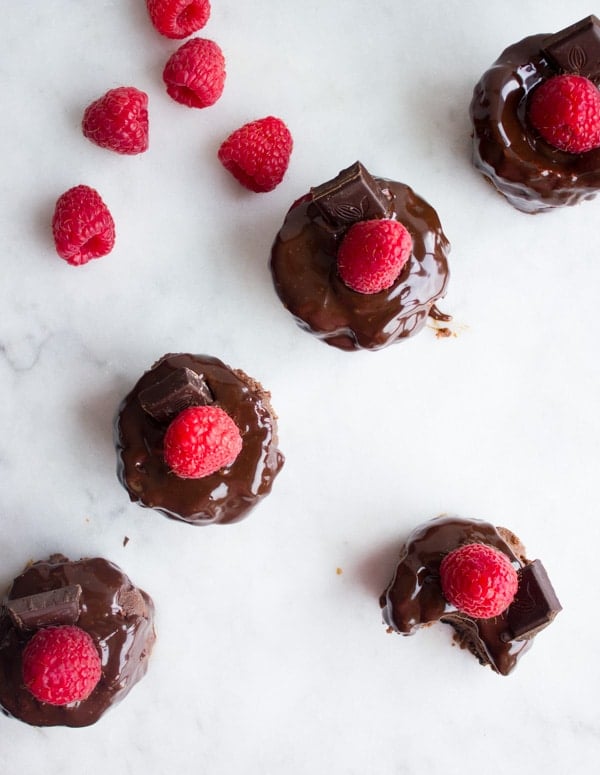 overhead shot of mini chocolate cheesecakes topped with chocolate sauce and raspberries