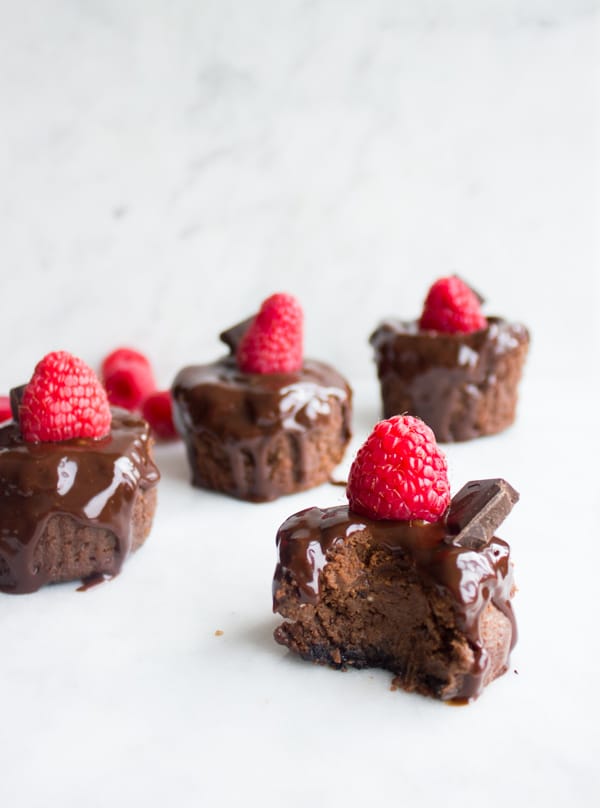 side view of Mini Chocolate Cheesecakes topped with fresh raspberries and chocolate sauce