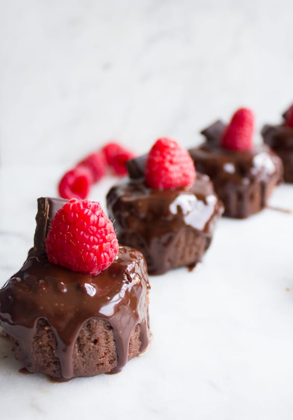 individual sized chocolate cheesecakes topped with fresh raspberries and chocolate sauce