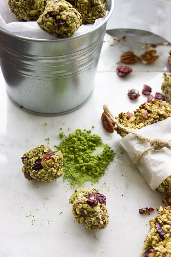 Banana Matcha Energy Bites on a white countertop with some matcha powder on the side