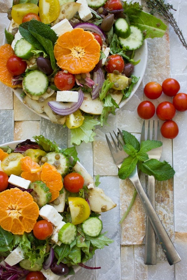 overhead shot of Orange Lentil Greek Salad with forks, fresh mint and tomatoes on the side