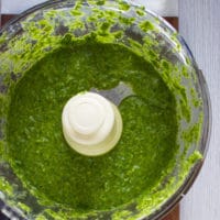 all ingredients for pistachio pesto in a food processor bowl blended and ready