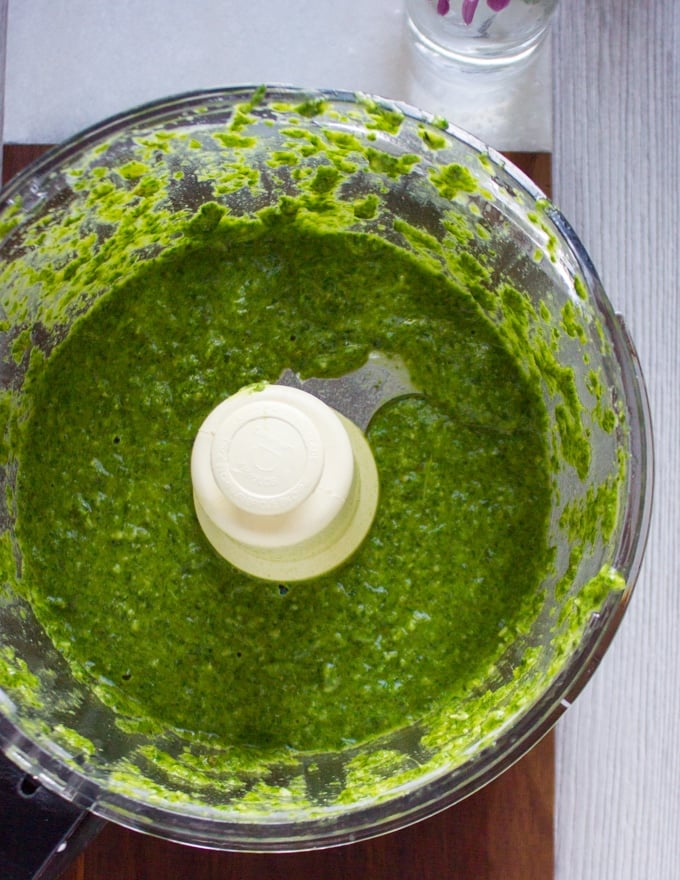 all ingredients for pistachio pesto in a food processor bowl blended and ready