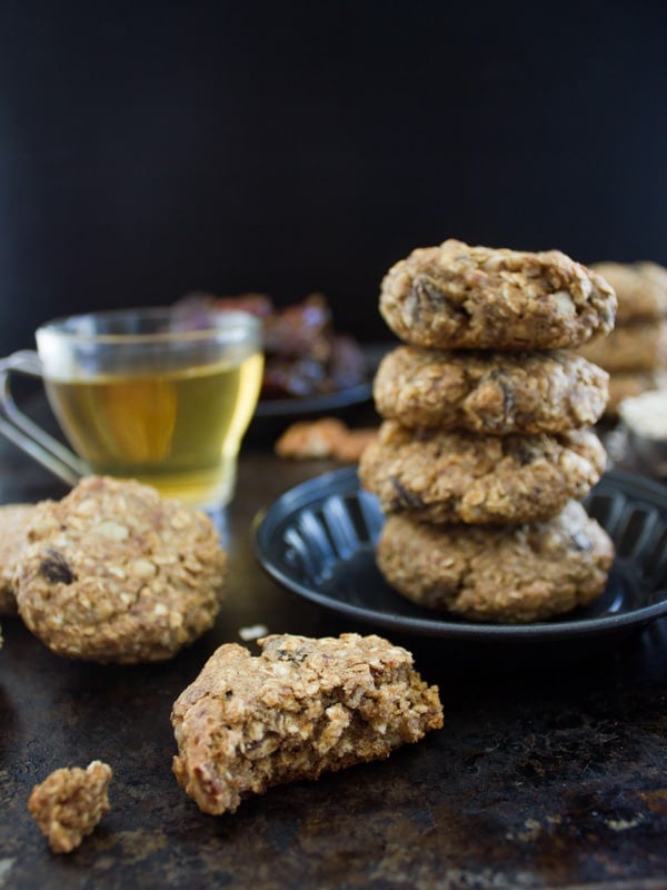 close-up of half a Vegan Oatmeal Raisin Cookie with a stack of cookies in the background